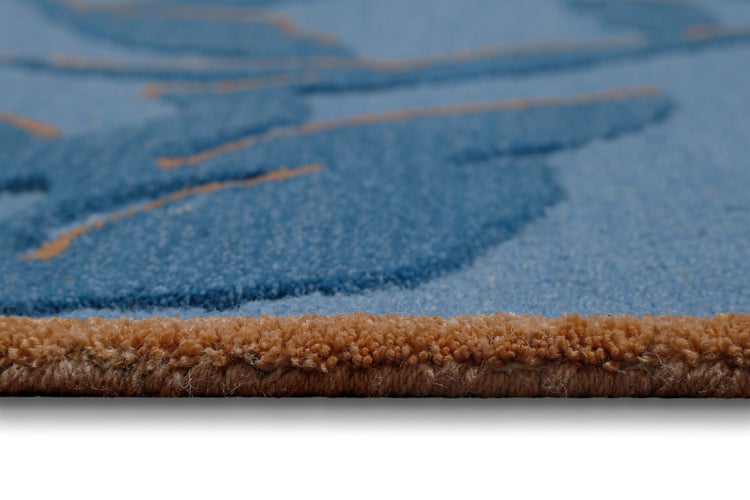 Nahaufnahme eines blau gemusterten Teppichs mit dickem Flor und einer orange-braunen Kante.