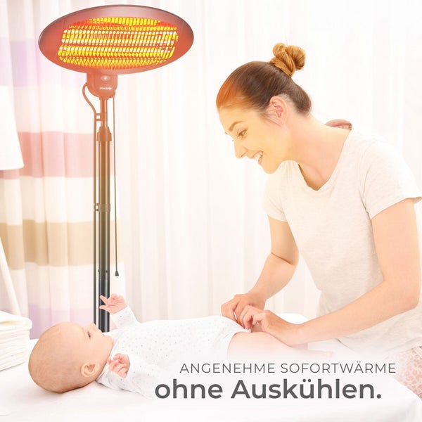 Mutter wickelt ihr Baby unter einem eingeschalteten Wickeltischstrahler, der für sofortige Wärme sorgt.