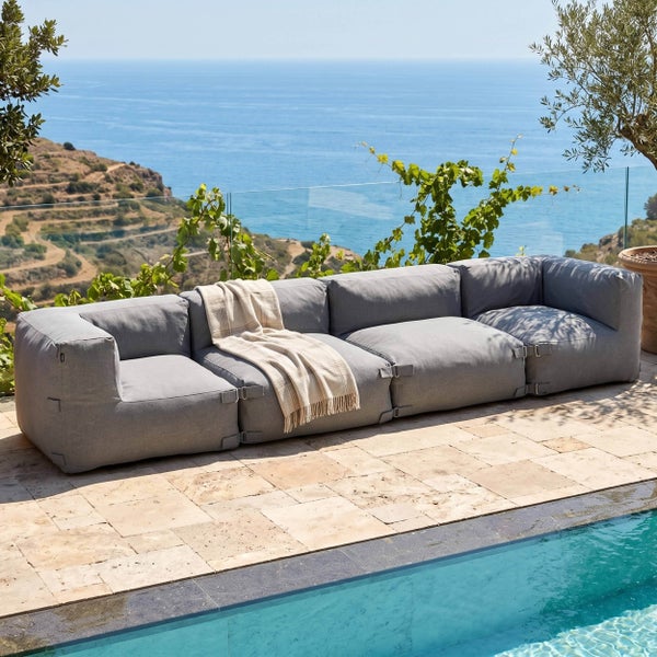 Modernes vierteiliges Outdoor-Modulsofa auf einer Steinterrasse am Pool mit Blick auf das Meer.