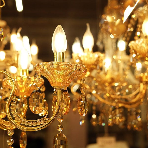 Kristallleuchter mit kerzenförmigen Leuchtmitteln und goldfarbenem Gestell.