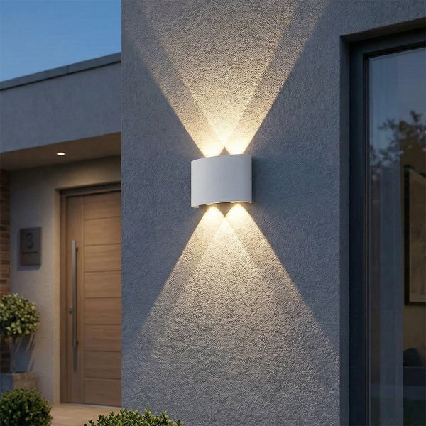 Moderne weiße Außenwandleuchte mit Lichtkegeln nach oben und unten an einer grauen Fassade neben einer Haustür.