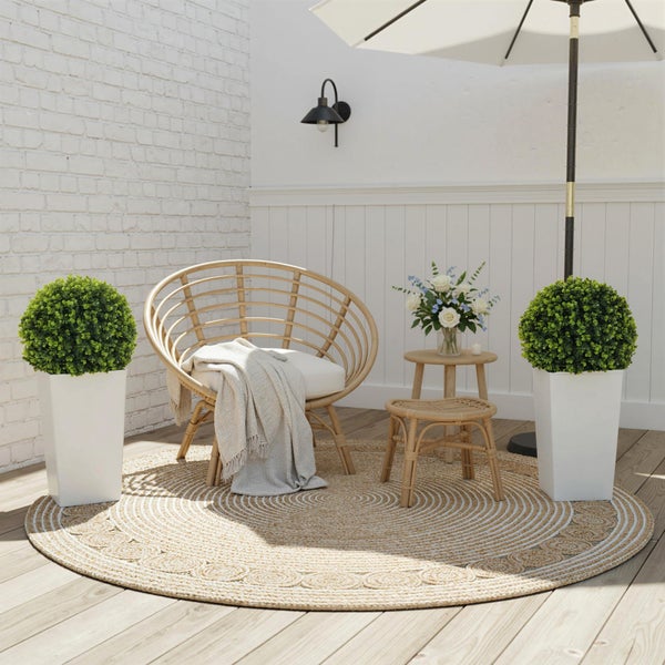 Terrasse mit Rattansessel, Beistelltisch, Dekoration und Sonnenschirm