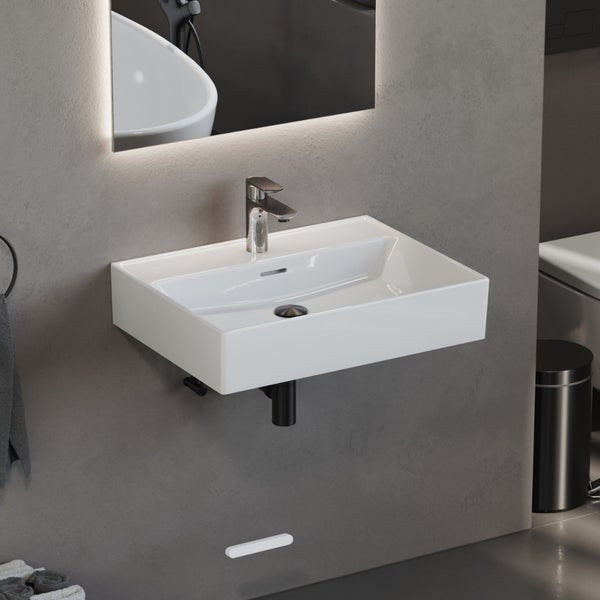Rechteckiges Wandwaschbecken aus Keramik mit Armatur und Siphon in einem modern eingerichteten Badezimmer mit beleuchtetem Spiegel.