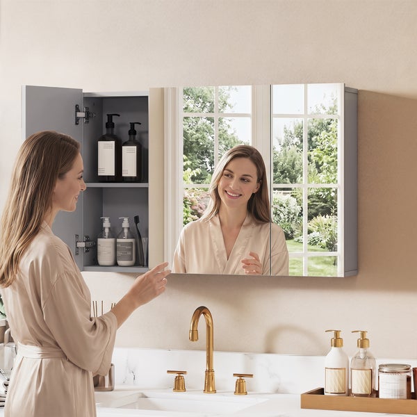 Spiegelschrank im Badezimmer mit drei Türen, eine Tür geöffnet mit Blick auf Innenfächer, moderner Waschtisch mit goldener Armatur.