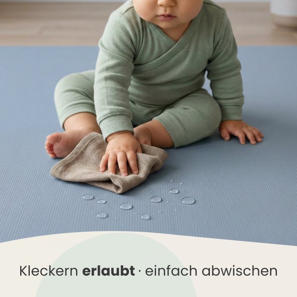 Ein Kleinkind wischt Wassertropfen von einer strukturierten Spielmatte ab. Text: Kleckern erlaubt - einfach abwischen.