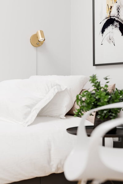 Schlafzimmer mit Bett, Nachttisch, Wandleuchte und Dekorationsgegenständen