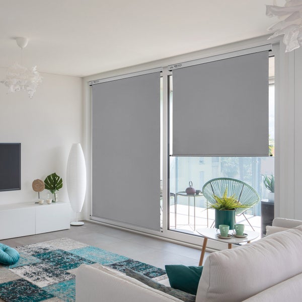 Wohnzimmer mit grauen Rollos an der Fensterfront für Sonnenschutz und Privatsphäre.