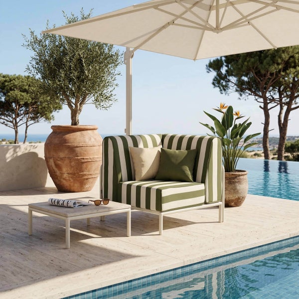 Modernes Lounge-Set mit gestreiftem Sessel und Beistelltisch auf einer Terrasse am Pool mit Sonnenschirm und Olivenbaum im Terrakottatopf.