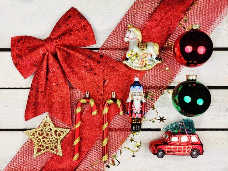 Set aus verschiedenen Weihnachtsbaumkugeln und Figuren wie Nussknacker, Schaukelpferd, Auto und Zuckerstangen mit roter Schleife.