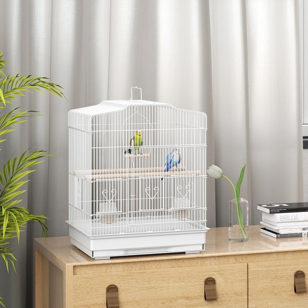 Vogelkäfig aus Metall auf einer Holzkommode mit zwei Wellensittichen, Sitzstangen und Futterschalen.