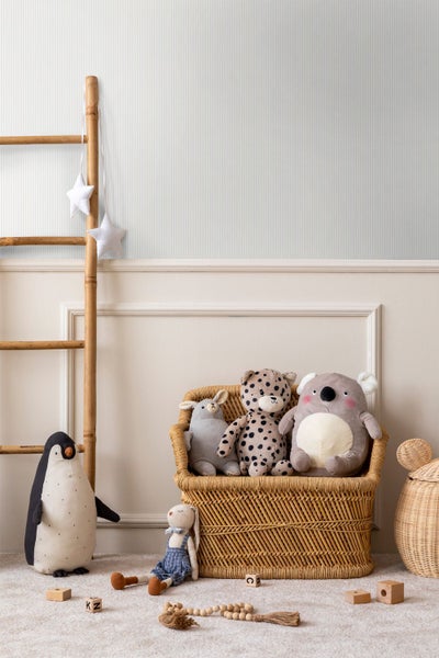 Helles Schlafzimmer mit gestreifter Tapete, einem Bett mit Stricküberwurf, einer offenen rustikalen Holztür und einem runden Jute-Teppich.