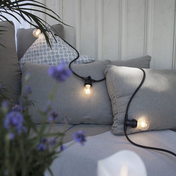 Dekorative Glühbirnenkette auf einem Sofa mit Kissen.