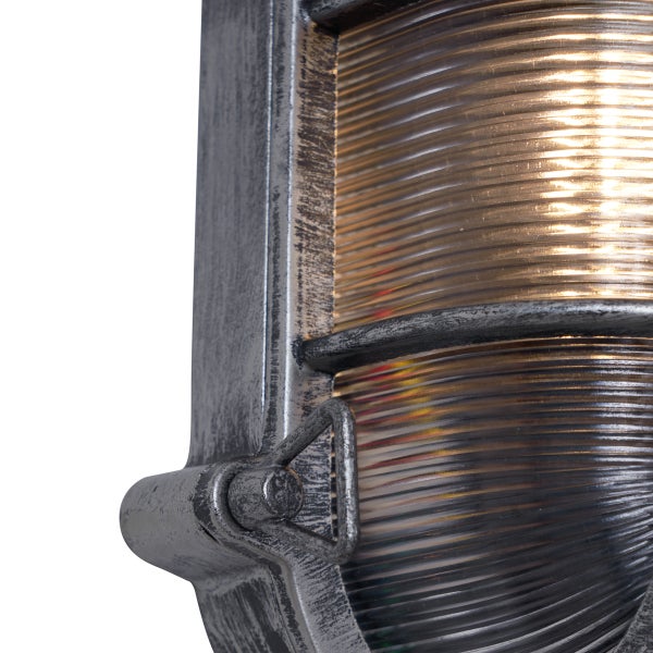 Nahaufnahme einer industriellen Außenwandleuchte mit silbernem Metallrahmen und geripptem Glas