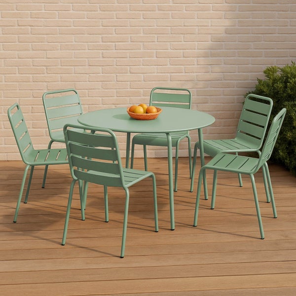 Gartenmöbel-Set bestehend aus einem runden Metalltisch und fünf grünen Stühlen auf einer Holzterrasse vor einer Ziegelwand.
