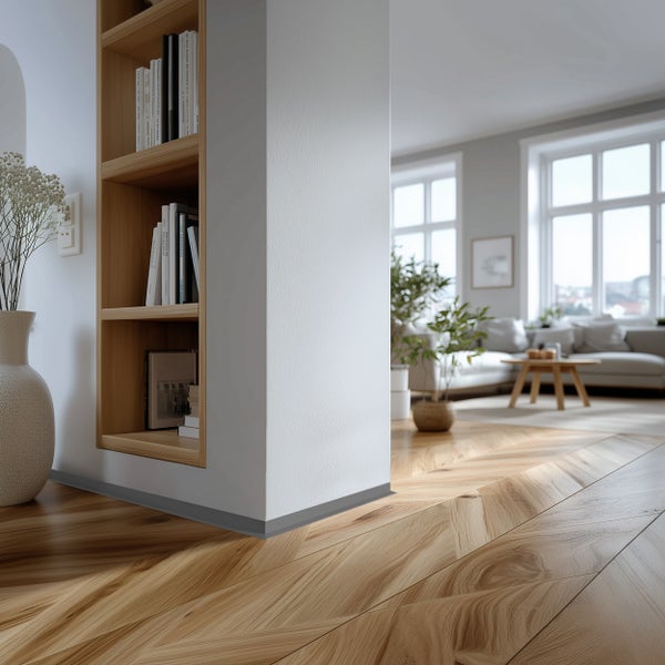 Helles Wohnzimmer mit Fischgrätparkett, integriertem Wandregal aus Holz und Übergang zum Wohnbereich mit Sofa und großen Fenstern.