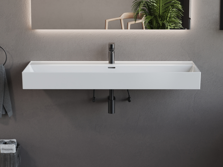 Modernes Wand-Waschbecken in Weiß, rechteckige Form, mit dunkler Armatur und Siphon unter einem beleuchteten Spiegel.