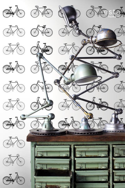 Drei Gelenkleuchten auf einem Schubladenschrank vor einer Tapete mit Fahrradmotiven.