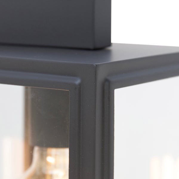 Detailansicht einer schwarzen Außenwandleuchte aus Metall und Glas mit sichtbarem Leuchtmittel.