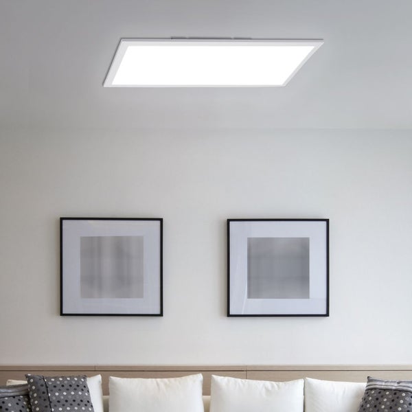Flaches, rechteckiges LED-Panel an der Decke über einer Wand mit Bildern und einem Sofa mit Kissen.