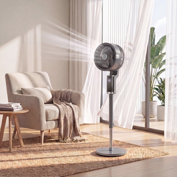 Moderner anthrazitfarbener Standventilator im hellen Wohnzimmer neben einem beigen Sessel und einem Fenster mit weißen Vorhängen.