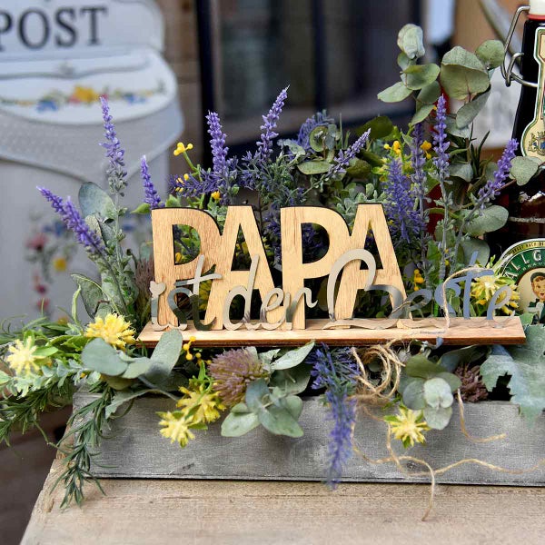 Dekorative Holzkiste mit der Aufschrift 'Papa ist der Beste' und Blumenarrangement