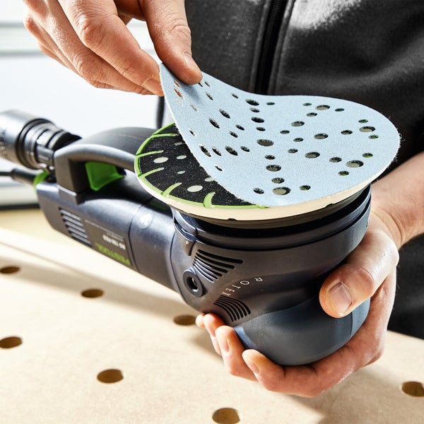 Ein Mann befestigt Schleifpapier an einem Exzenterschleifer