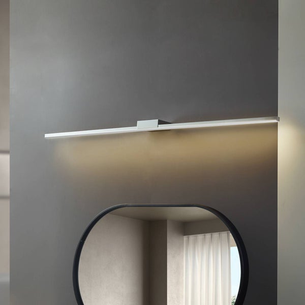 Schlanke LED-Spiegelleuchte in Chrom-Optik, horizontal über einem ovalen Spiegel montiert, mit warmem, nach unten gerichtetem Licht.