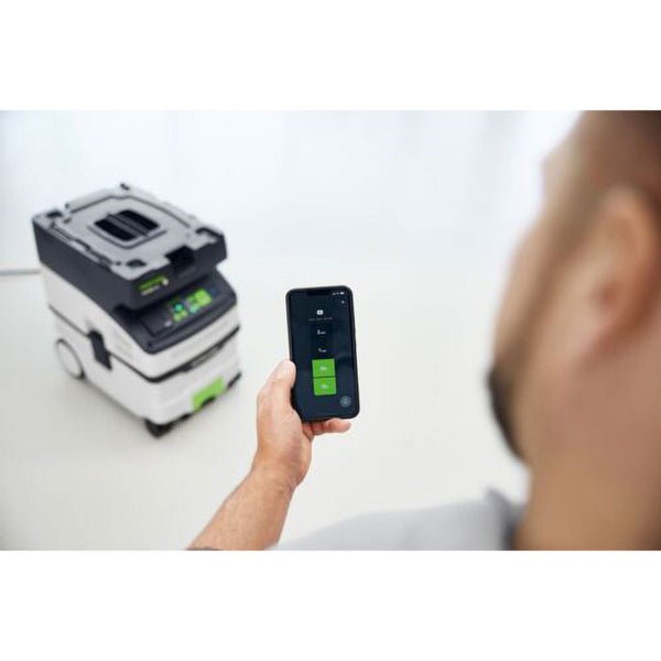 Person steuert einen Festool Staubsauger über eine Smartphone App für bequeme Fernbedienung und Gerätesteuerung.