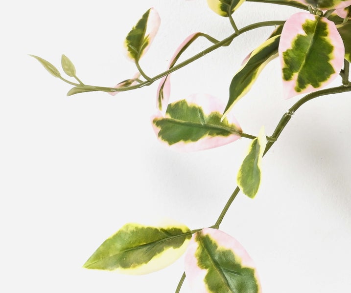 Künstlicher Pflanzenzweig mit grün-rosa gemusterten Blättern und strukturiertem Kunststoffstiel.