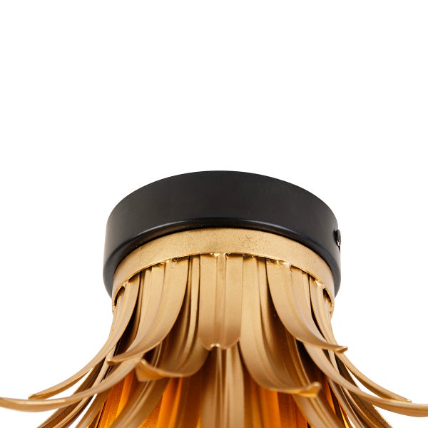 Detailaufnahme einer Deckenleuchte mit goldenen Lamellen und schwarzer Deckenbefestigung.