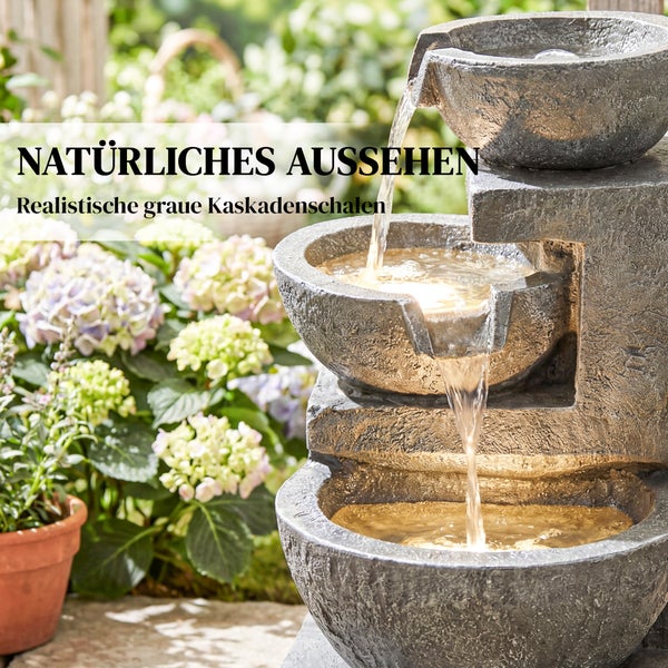 Drei-stufiger Kaskadenbrunnen in Steinoptik mit fließendem Wasser in einer Gartenlandschaft mit Hortensien.