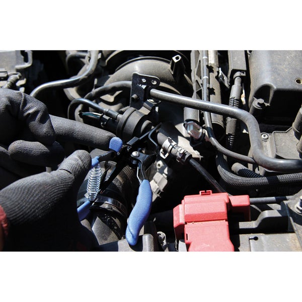 Detailaufnahme von einem Motorraum mit einer Person, die mit Handschuhen an den Schläuchen arbeitet.