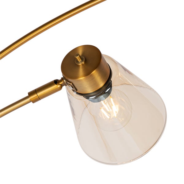 Detailaufnahme einer goldenen Lampe mit einem Lampenschirm aus Glas