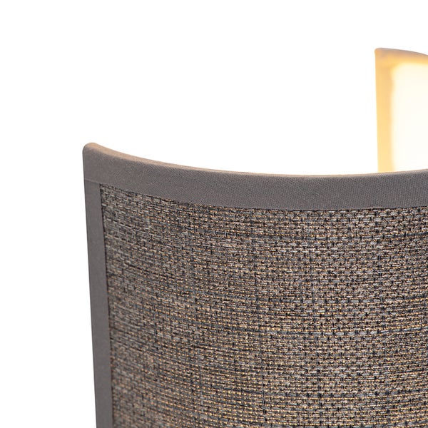 Nahaufnahme eines gewebten Lampenschirms einer Wandleuchte aus Stoff mit strukturierter Oberfläche und glatter Einfassung.