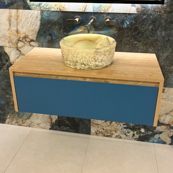 Moderner wandhängender Waschtischunterschrank mit Holzoptik-Rahmen, blauer Front und rundem Naturstein-Aufsatzwaschbecken.
