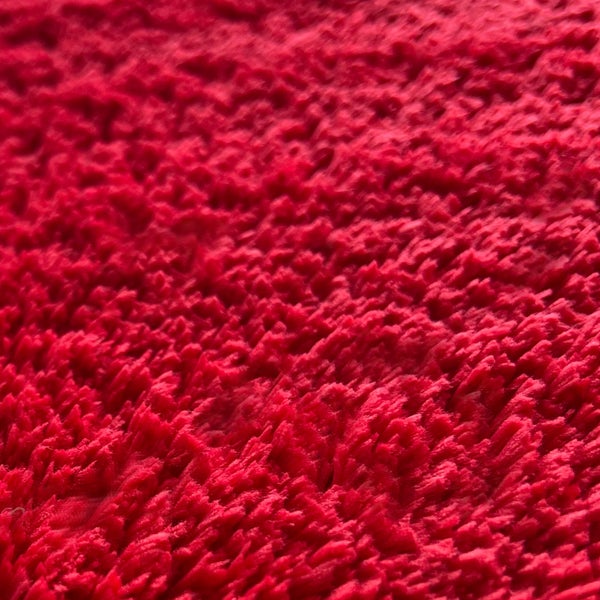 Nahaufnahme eines roten, hochflorigen Teppichs.