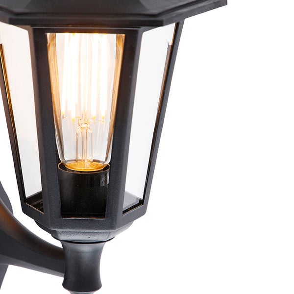 Detailansicht einer Außenwandleuchte in Laternenform mit schwarzem Gehäuse und leuchtender LED-Filament-Glühbirne hinter klarem Glas.
