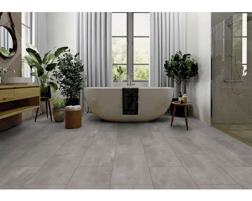 Helles Badezimmer mit freistehender Badewanne, Waschtisch und grauen Bodenfliesen.