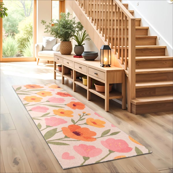 Heller Flur mit einem Teppichläufer mit Blumenmuster, einer Holztreppe und einem Sideboard mit Pflanzen auf einem Holzfußboden.
