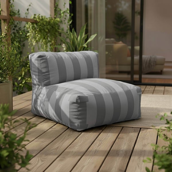 Moderner, armloser Outdoor-Loungesessel mit grauen Längsstreifen auf einer Holzterrasse, umgeben von grünen Pflanzen.