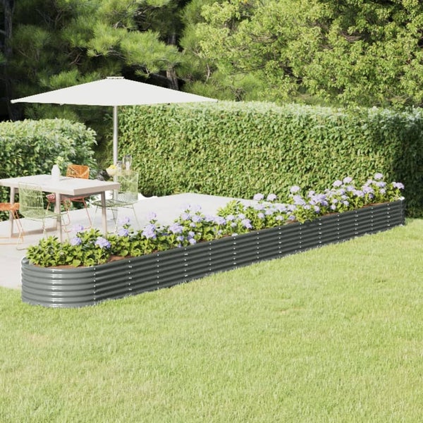 Gartenansicht mit erhöhtem, bepflanztem, grauem Metallbeet, Esstischgruppe und Sonnenschirm