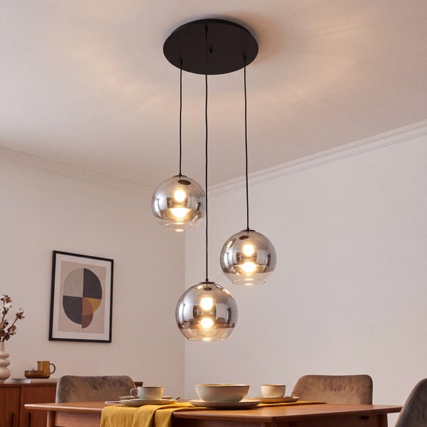 Dreiflammige Pendelleuchte mit runden Glaskugeln über einem Holzesstisch im Esszimmer.