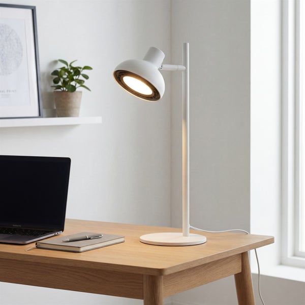 Weiße Schreibtischleuchte auf einem Schreibtisch aus Holz in einem hellen, modern eingerichteten Arbeitszimmer mit Laptop und Pflanze.