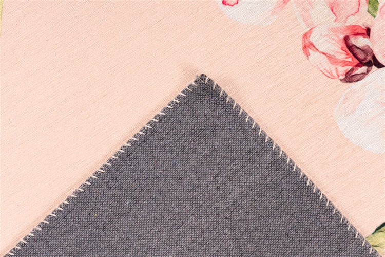 Detailansicht eines Teppichs mit Blumenmuster und grauer Rückseite mit Kettelung am Rand.