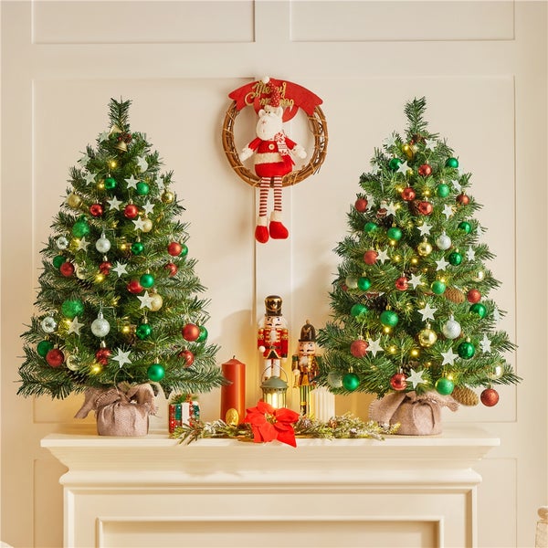 Dekorierter Kaminsims mit zwei Weihnachtsbäumen, Nussknackern, Kerze und Weihnachtsschmuck