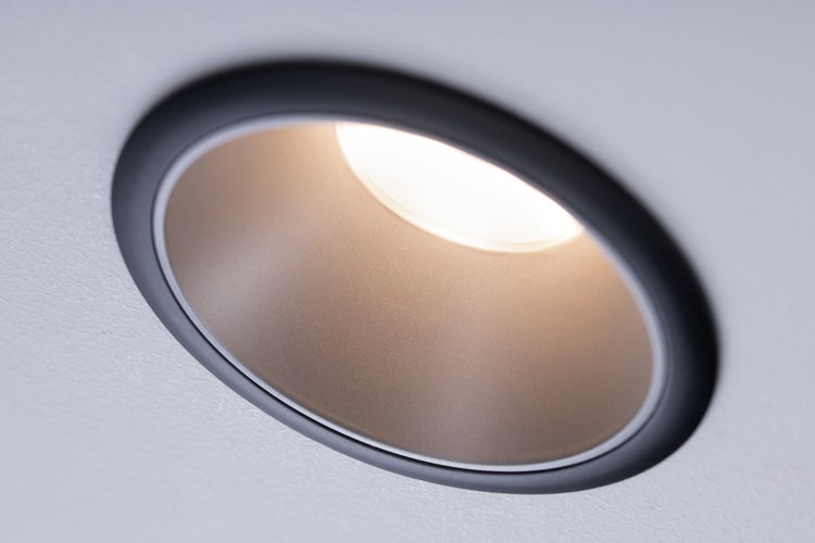 Runder Einbaustrahler in Schwarz und Gold mit warmweißem Licht.