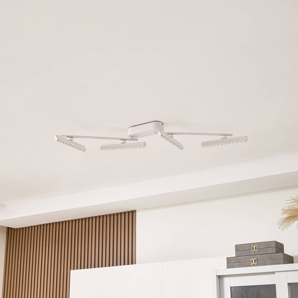 Moderne LED-Deckenleuchte in Weiß mit vier verstellbaren Armen und flachen Leuchtköpfen an einer weißen Zimmerdecke.