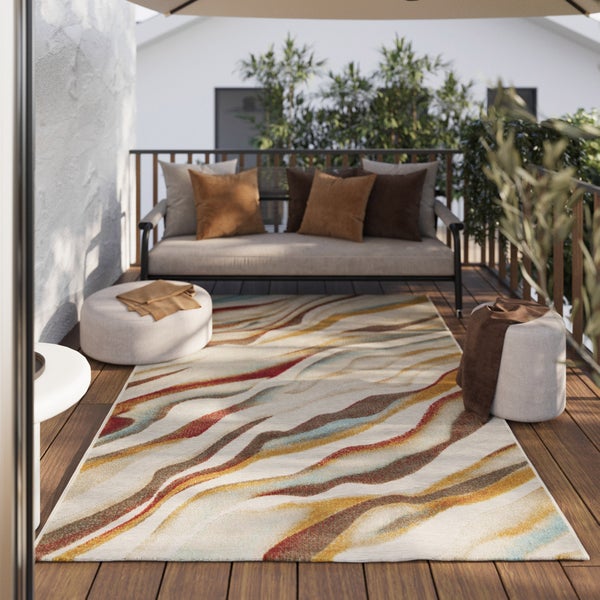 Outdoor-Teppich mit abstraktem Wellenmuster in Erdtönen auf einem Balkon mit Holzdiele, Lounge-Sofa und Poufs.