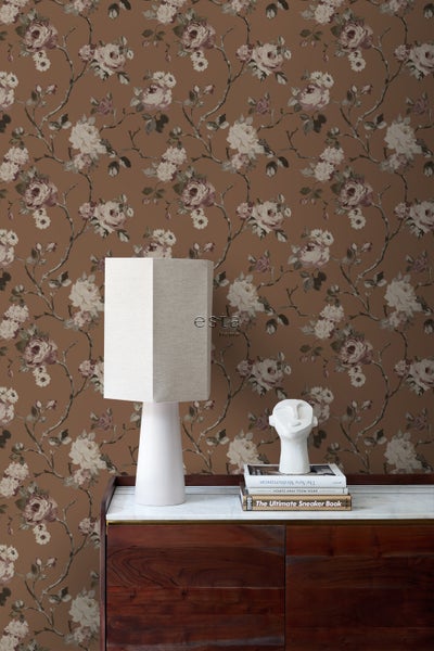 Dekoratives Zimmer mit einer Tapete mit Rosenmuster, einer Lampe und einer Kommode.