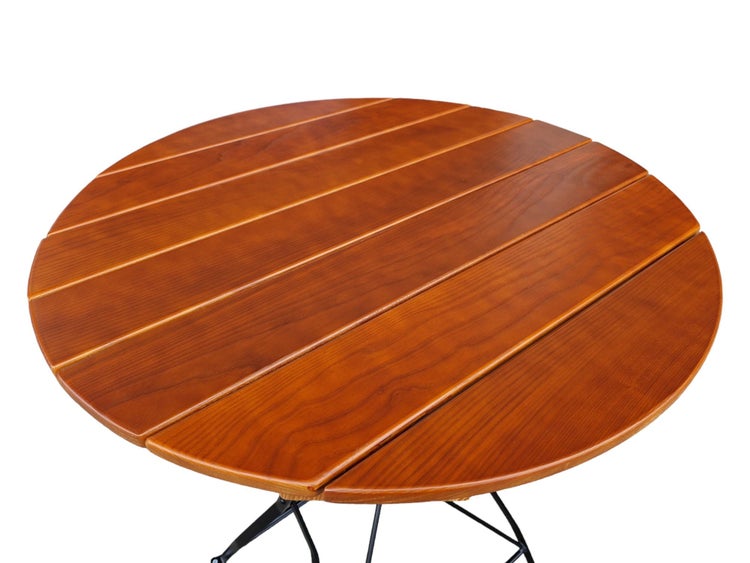 Runde Tischplatte aus Holzlatten mit rötlich-brauner Oberfläche und schwarzem Metallgestell.